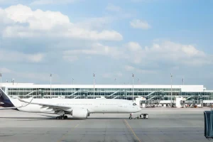 Passeggeri in coda al bancone di imbarco di un aeroporto con aerei sullo sfondo