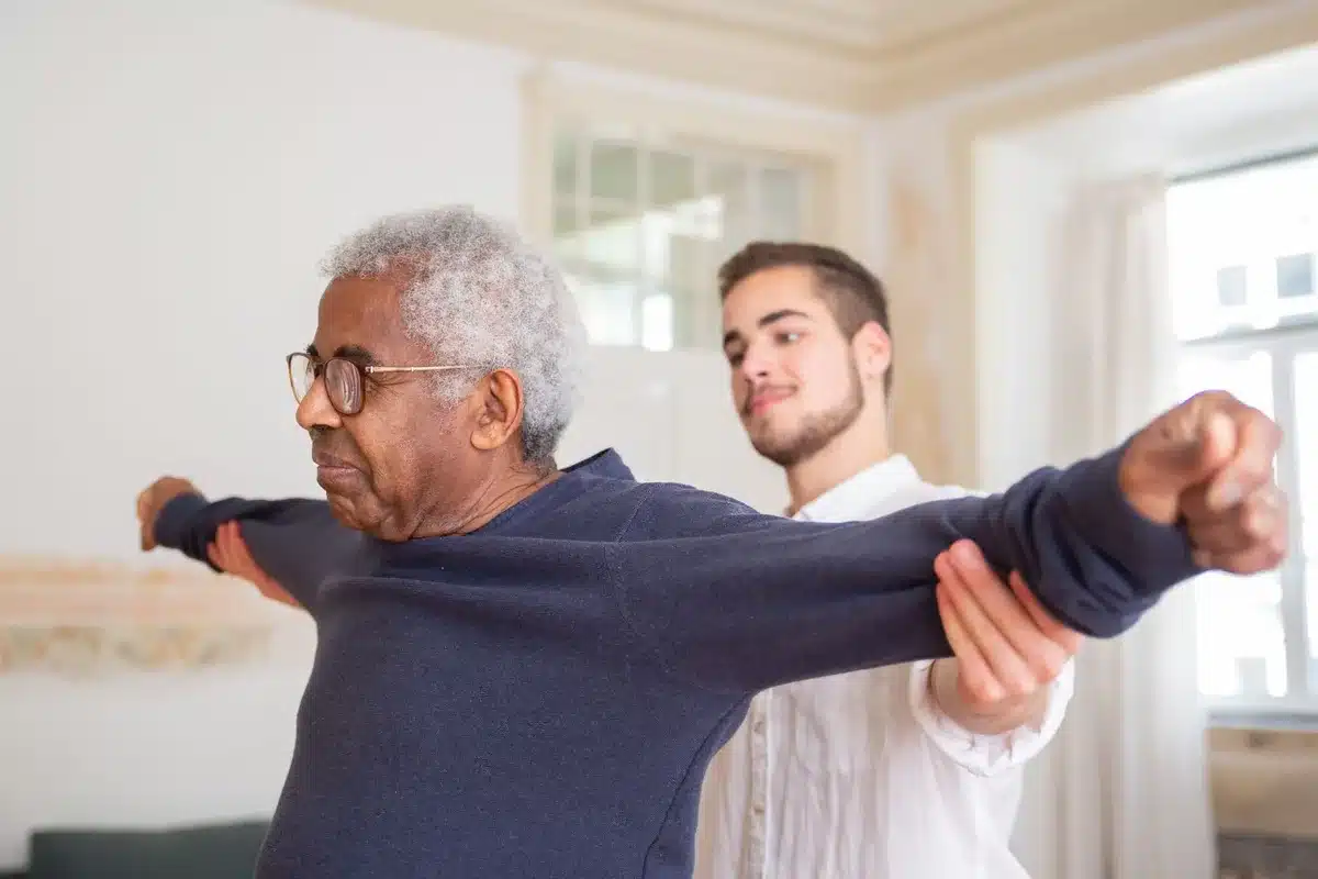 Le mani di un caregiver sostengono il braccio di una persona anziana in un ambiente domestico