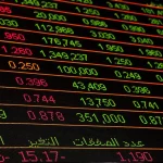 Documenti finanziari e grafici di mercato su una scrivania di trading con calcolatrice