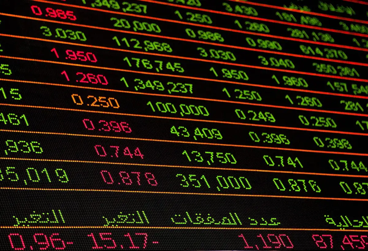 Documenti finanziari e grafici di mercato su una scrivania di trading con calcolatrice