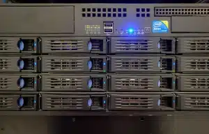 Corridoio di un data center con rack server e una mano anonima al pannello di controllo