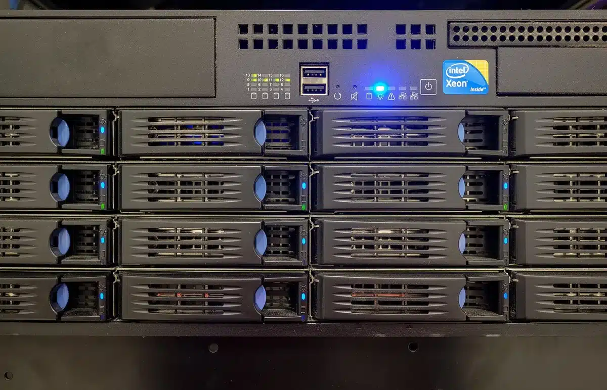Corridoio di un data center con rack server e una mano anonima al pannello di controllo