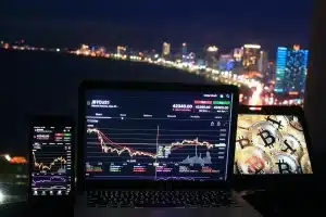 Mani anonime che analizzano grafici di borsa su un laptop in ufficio luminoso
