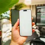 Mani che tengono uno smartphone pieghevole aperto su una scrivania, vista 4:3