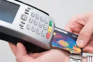 Banco di negozio anonimo con terminale di pagamento e monete impilate